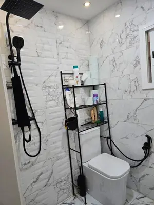 a bathroom with a toilet and a white marble wall at Apartamento Moderno, amplio y muy cómodo in Terrassa