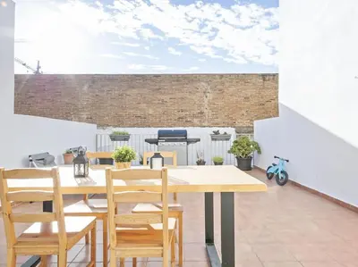 a dining room with a wooden table and chairs at La Terraza de Badalona in Badalona