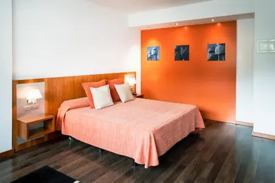 a bedroom with a bed with an orange wall at AS Porta de Barcelona in Castellbisbal