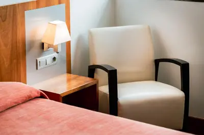 a bedroom with a bed and a chair and a lamp at AS Porta de Barcelona in Castellbisbal