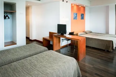 a room with two beds and a desk with a television at AS Porta de Barcelona in Castellbisbal