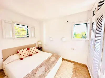 a white bedroom with a bed and two windows at Solaui in Esplugues de Llobregat