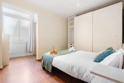 a bedroom with a large white bed and a window at Lodging Apartments Entenca in Barcelona