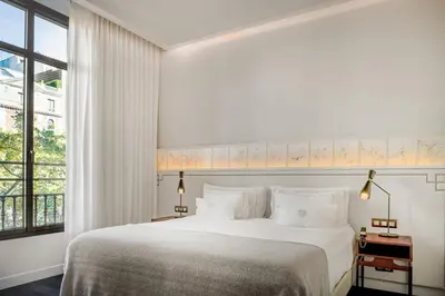 a white bedroom with a large bed and a window at Cotton House Hotel, Autograph Collection in Barcelona