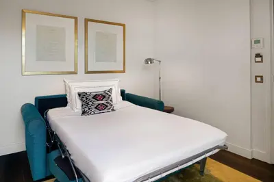 a white bed with a pillow on it in a room at Cotton House Hotel, Autograph Collection in Barcelona