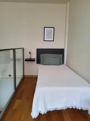 a bedroom with a bed with white sheets and wood floors at SUITE apartamento in Barcelona
