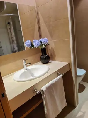 a bathroom with a sink and a vase with purple flowers at SUITE apartamento in Barcelona
