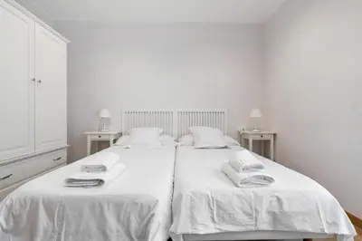 a white bedroom with two beds with white sheets at Flateli Pelayo H2 in Barcelona