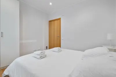 a white bedroom with two white beds with towels on them at Flateli Pelayo H2 in Barcelona