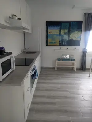 a kitchen with white cabinets and a table at Loft espectacular vista al mar in Sitges