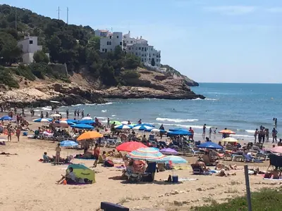 a group of people on a beach with umbrellas at Loft espectacular vista al mar in Sitges