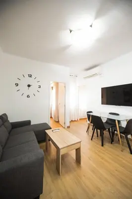 a living room with a couch and a clock on the wall at Casa a pasos de Las Ramblas in Barcelona