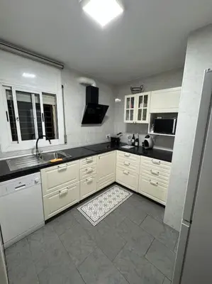 a kitchen with white cabinets and a black counter top at Casa con piscina uso privado in Cunit