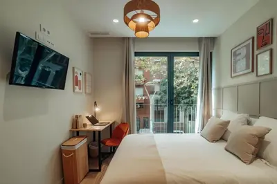 a bedroom with a bed and a desk and a window at Casa Carlit - 1 bedroom apartment near Plaza Tetuán in Barcelona