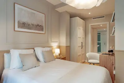a bedroom with a white bed and a chair at Casa Dorada in Barcelona