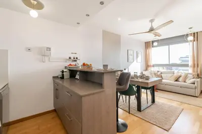 a kitchen and living room with a table and a couch at Penthouse with Private Terrace & Pool Access in Cornellà de Llobregat