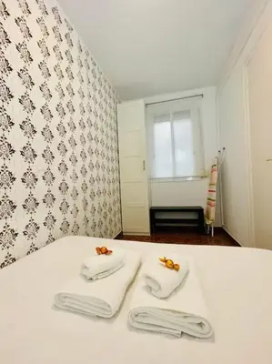 a bed with two white towels and a window at Plaza España - Central and quiet 2BR for couples, families and events in Barcelona