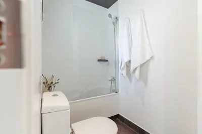 a white bathroom with a toilet and a bath tub at Casa Gavina in Barcelona