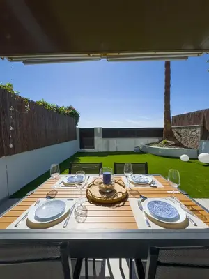 a wooden table with plates and wine glasses on it at Apartamento en la playa in Castelldefels