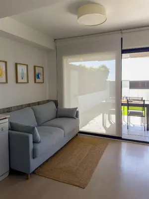 a living room with a couch and a sliding glass door at Apartamento en la playa in Castelldefels