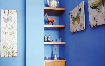 a blue wall with wooden shelves with dolls and butterflies at Lovely Home In St Cebrià De Vallalta in Sant Cebrià de Vallalta