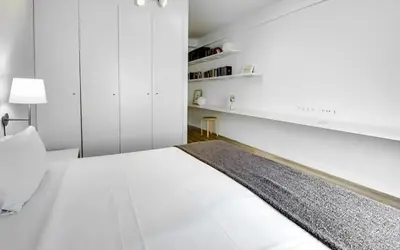 a white bedroom with a bed and white cabinets at Urban Flats Park Guell in Barcelona