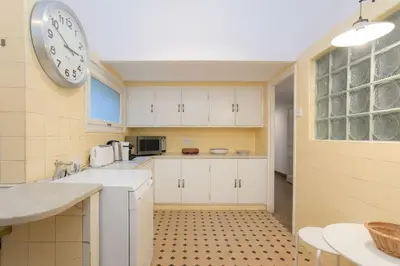 a kitchen with white cabinets and a clock on the wall at Canela Homes BARCELONA CASA SERRA in Barcelona