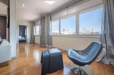 a living room with a blue chair and large windows at Canela Homes BARCELONA CENTRAL in Barcelona