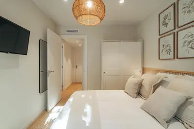 a bedroom with a large white bed and a television at Casa Marina in Barcelona