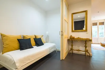 a white bed with yellow pillows and a mirror at Dana - Enjoy Apartments Rocafort in Barcelona