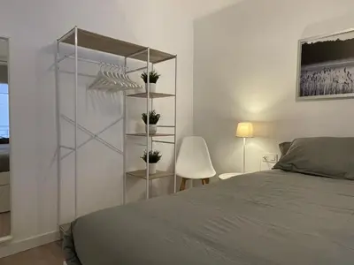a white bedroom with a bed and a chair at 15 min en metro a Sagrada Familia in Sant Adria de Besos