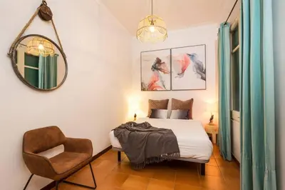 a bedroom with a bed and a chair and a mirror at Canela Homes BARCELONA INDÚSTRIA in Barcelona
