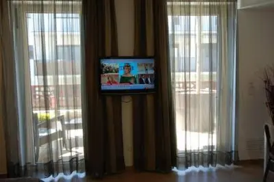 a television on a wall next to two large windows at Resort Sitges Apartment in Sitges