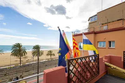 a balcony with flags and a beach at Hotel Llar de Capitans in Masnou
