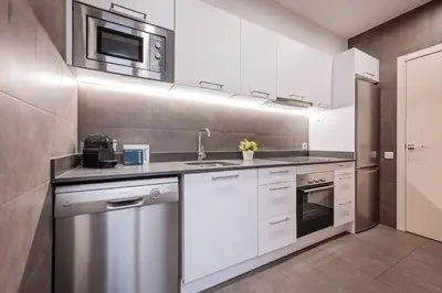 a kitchen with white cabinets and a sink and a microwave at Sweett - La Gran Via in Barcelona