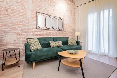 a living room with a green couch and a brick wall at Sweett - Urgell Eixample in Barcelona