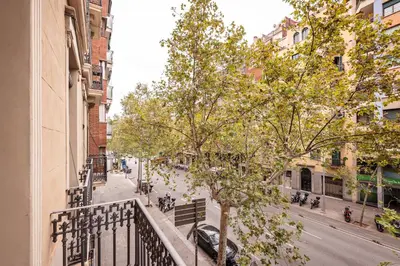a balcony of a building with a tree on a street at Sweett - Urgell Eixample in Barcelona