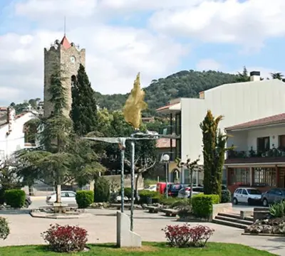 a building with a clock tower in a parking lot at Vista Alegre Casa Rest House in Vallromanas