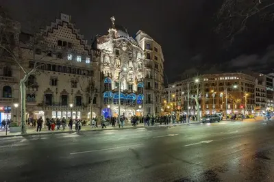 a city street at night with people crossing the street at Casa modernista en Paseo de Gracia in Barcelona