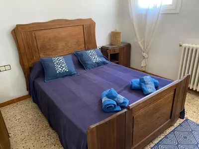 a bedroom with a large wooden bed with blue pillows at villa 7 personnes 45 mn Barcelone vue sur Montserrat in Vacarisas
