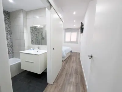 a white bathroom with a sink and a bed at New flat in the centre, 10 min from BCN Airport in Cornellà de Llobregat