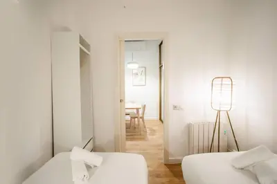 a white room with two beds and a table at Fantástico piso en Barcelona in Barcelona