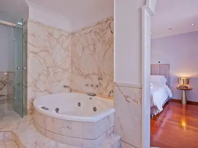 a bathroom with a bath tub and a bedroom at Habitas Stay Barcelona in Barcelona