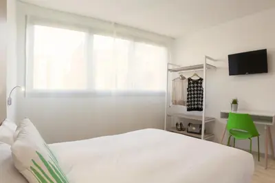 a white bedroom with a bed and a window at SmartRoom Barcelona in Barcelona