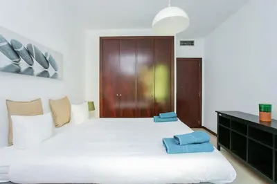 a bedroom with a large white bed with blue pillows on it at Canela Homes BARCELONA MONUMENTAL in Barcelona