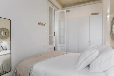 a white bedroom with a bed with white pillows at Casa Ribera in Barcelona