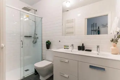 a white bathroom with a toilet and a glass shower at Casa Atlas in Barcelona