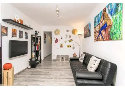 a living room with a black couch and a tv at Apartamento BB in Hospitalet de Llobregat