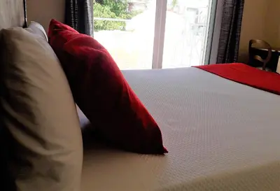 a bed with red and white pillows and a window at Hotel Noucentista in Sitges