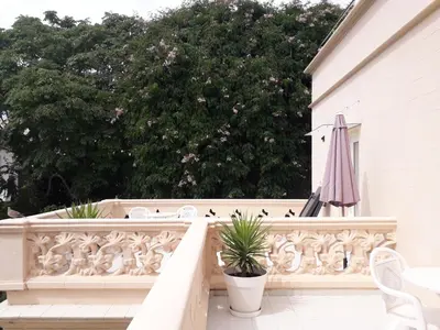 a white balcony with white chairs and an umbrella at Hotel Noucentista in Sitges